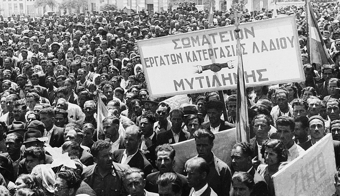 Εργατική Πρωτομαγιά 1945 στο σημερινό Δημοτικό Πάρκο Αγίας Ειρήνης Μυτιλήνης. Απέναντι φαίνονται οι τότε Αποθήκες Πετρόπουλου (μετέπειτα κινηματογράφος «ΑΡΙΩΝ») και η σημερινή Δημόσια Κεντρική Βιβλιοθήκη Μυτιλήνης στην οδό Σμύρνης (Αρχείο λεσβιακής εφημερίδας «Νέο Εμπρός»). 